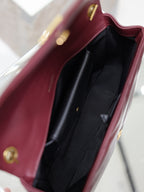 Burgundy shoulder bag interior with black lining and slip pocket, gold snap details.