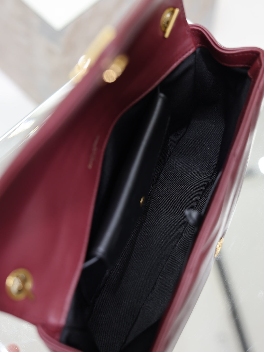 Burgundy shoulder bag interior with black lining and slip pocket, gold snap details.
