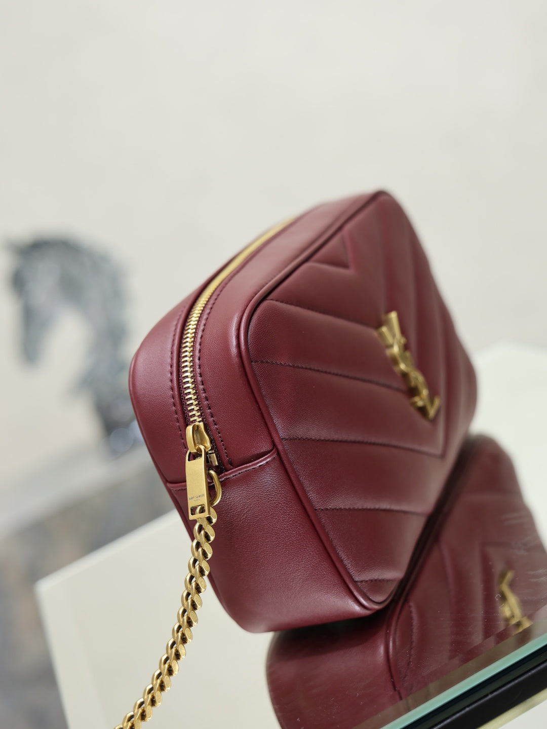 YSL bag back view in burgundy with gold chain strap and vertical stitched panels