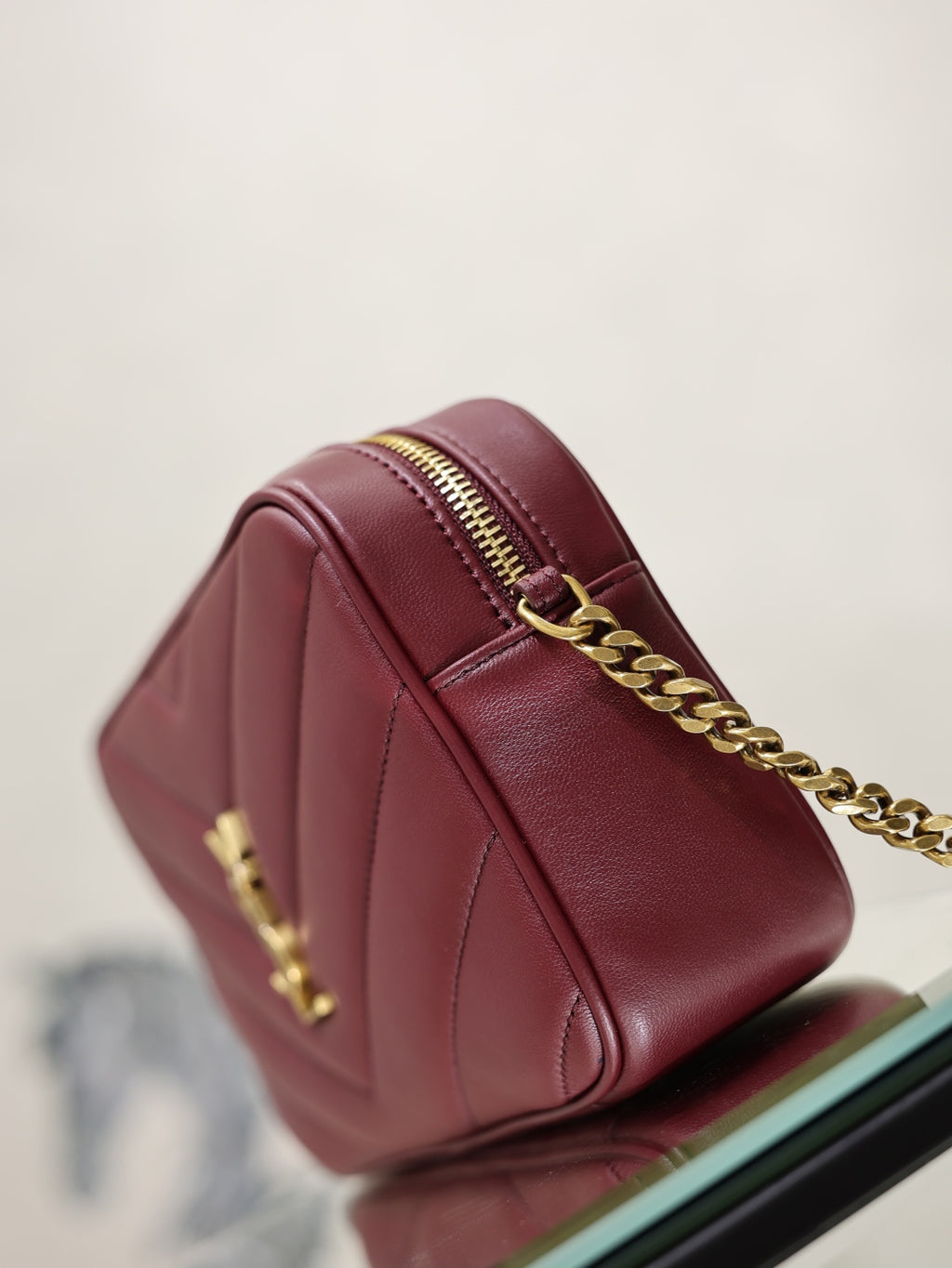 YSL bag side view in burgundy leather with gold chain and top zip detail