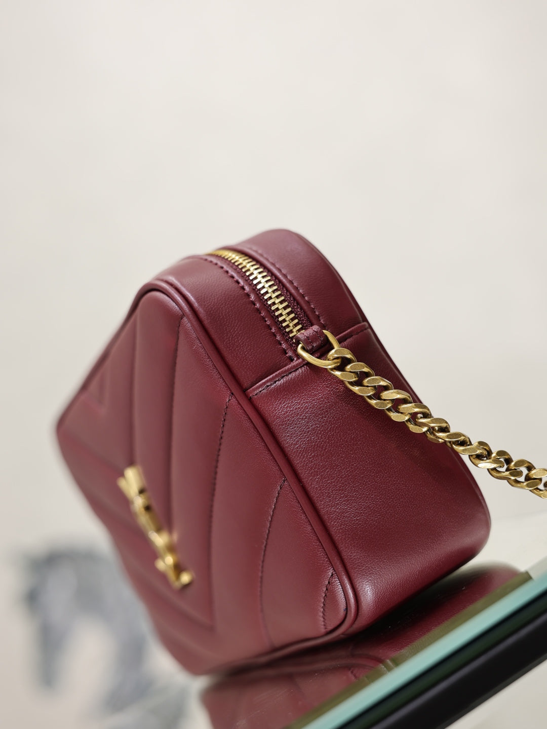 YSL bag side view in burgundy leather with gold chain and top zip detail