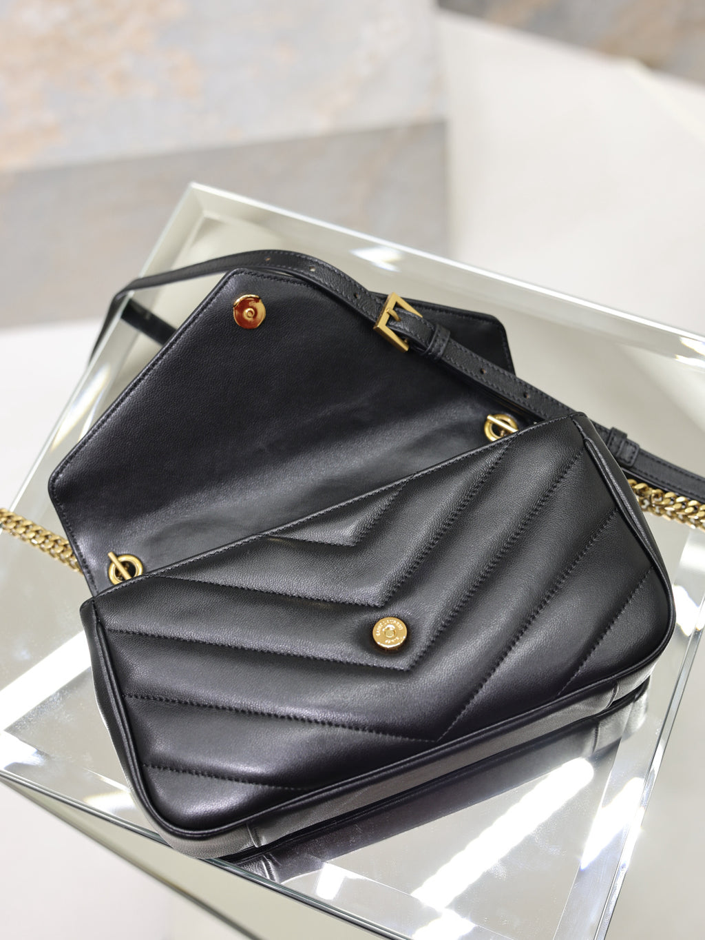 Black quilted shoulder bag on display with gold hardware and flap closure