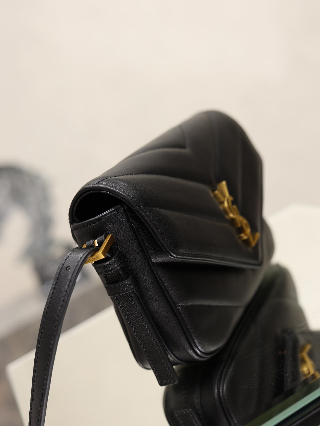 Black YSL mini bag with quilted texture and gold hardware, side view