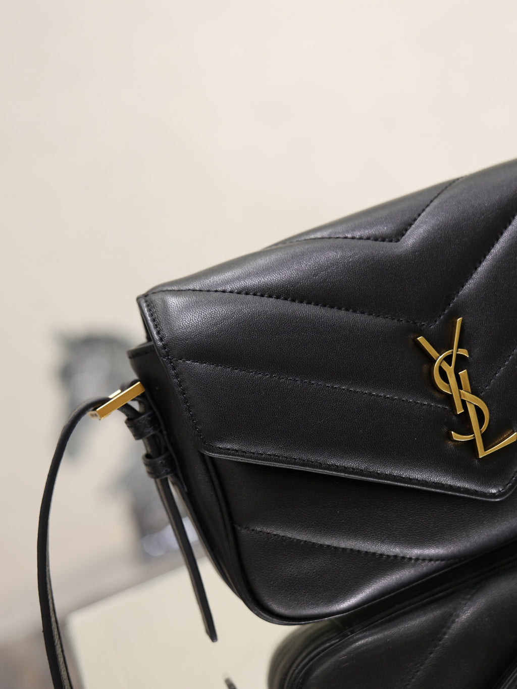 Black YSL bag close-up with gold logo on quilted front flap