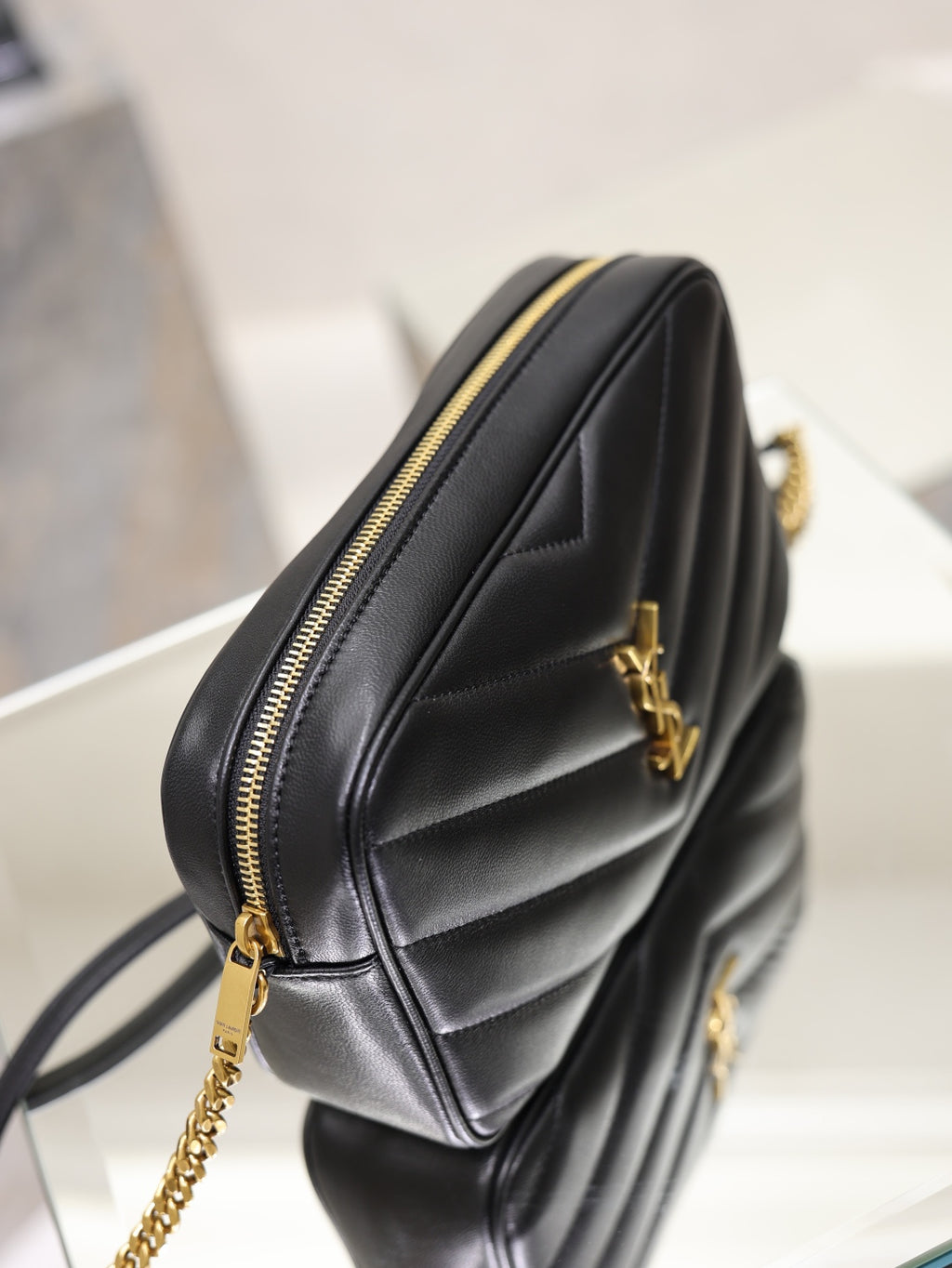 YSL quilted shoulder bag, black leather side angle with gold zipper trim and chain