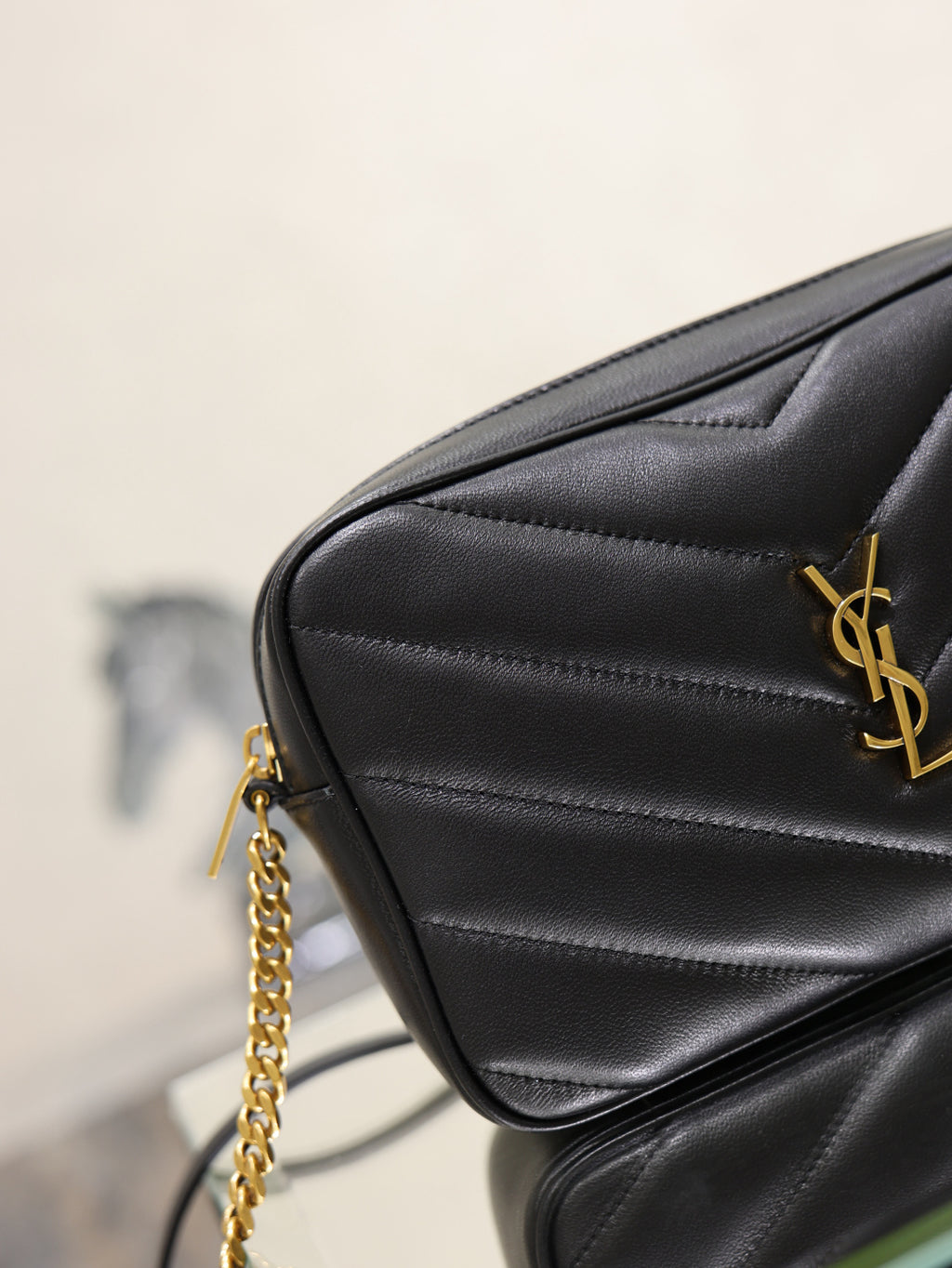 YSL quilted shoulder bag side view, black leather with gold YSL logo pin