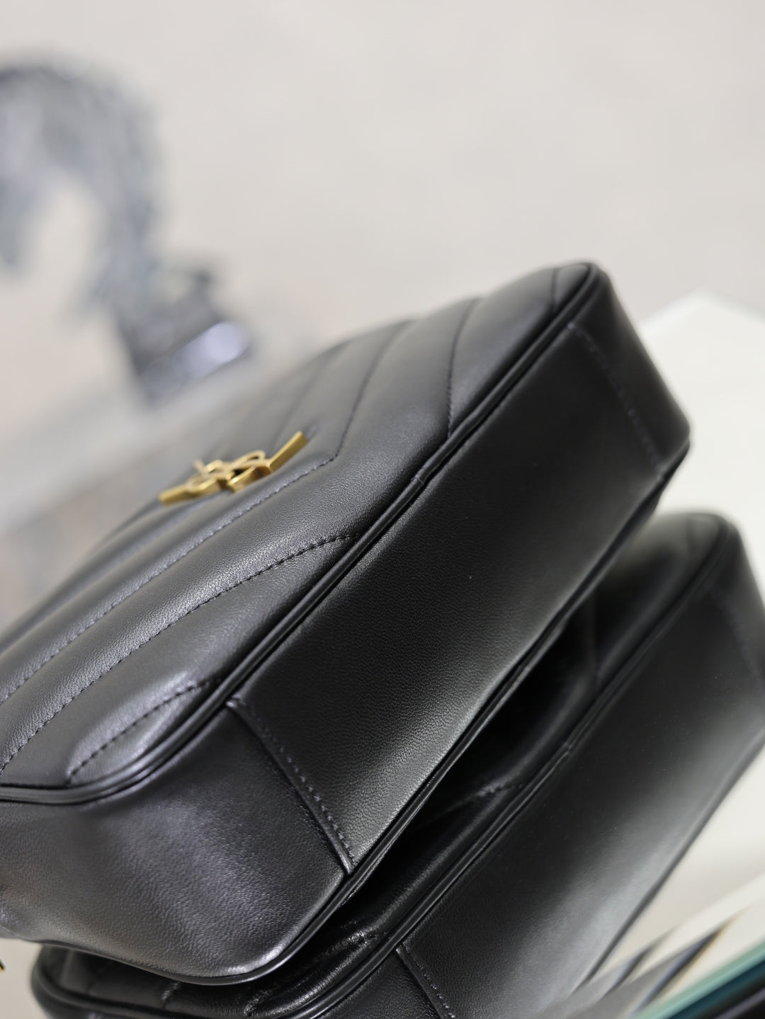 YSL shoulder bag close-up, black leather top edge with gold logo hardware