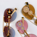 Gold-tone sunglasses with round emblem details and tinted mirrored lenses
