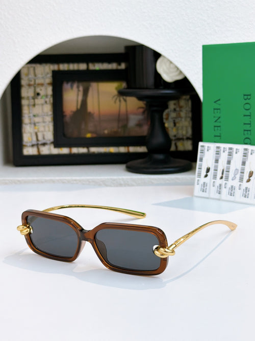 Glasses with dark brown lenses, tortoiseshell frames, and gold curved temples