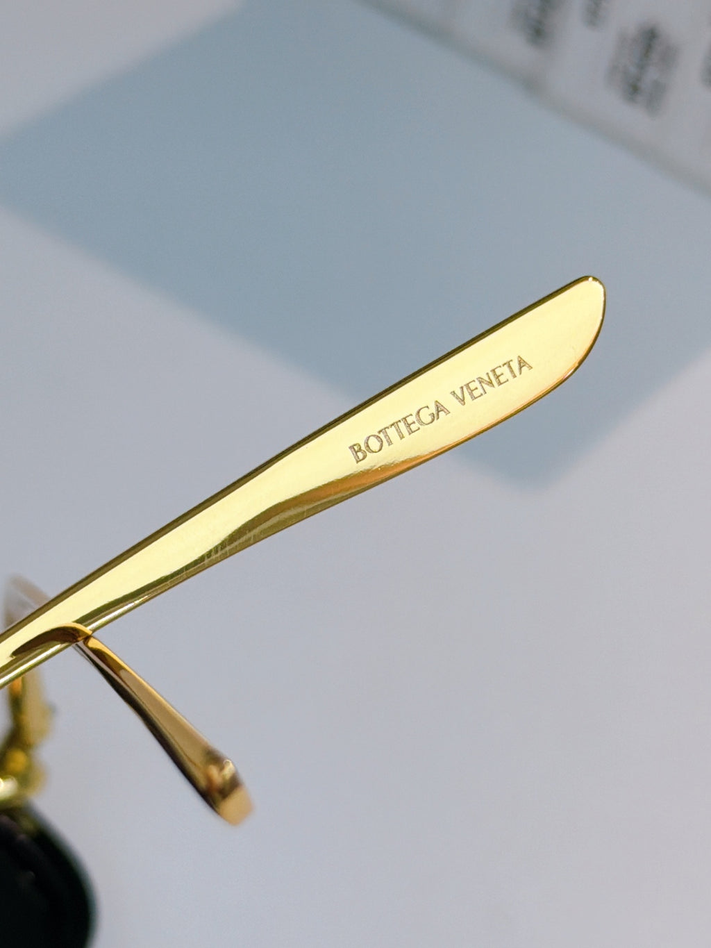 Glasses temple detail with gold arm and engraved BOTTEGA VENETA