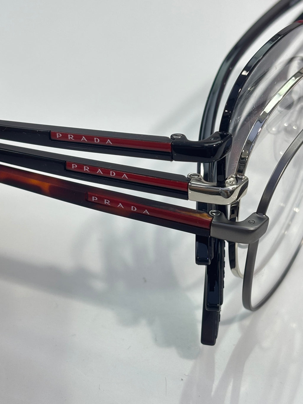 Eyeglasses with dark temple arms showing red and black PRADA lettering.