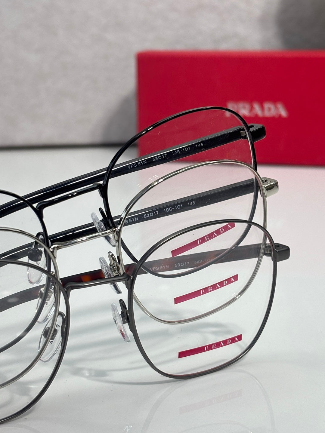 Overlapping eyeglasses with dark round frames and clear lenses.
