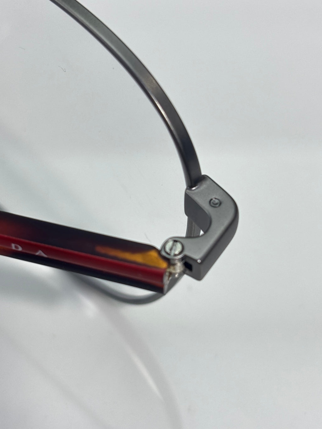 Eyeglasses temple tip with dark frame and red-brown accent on arm.