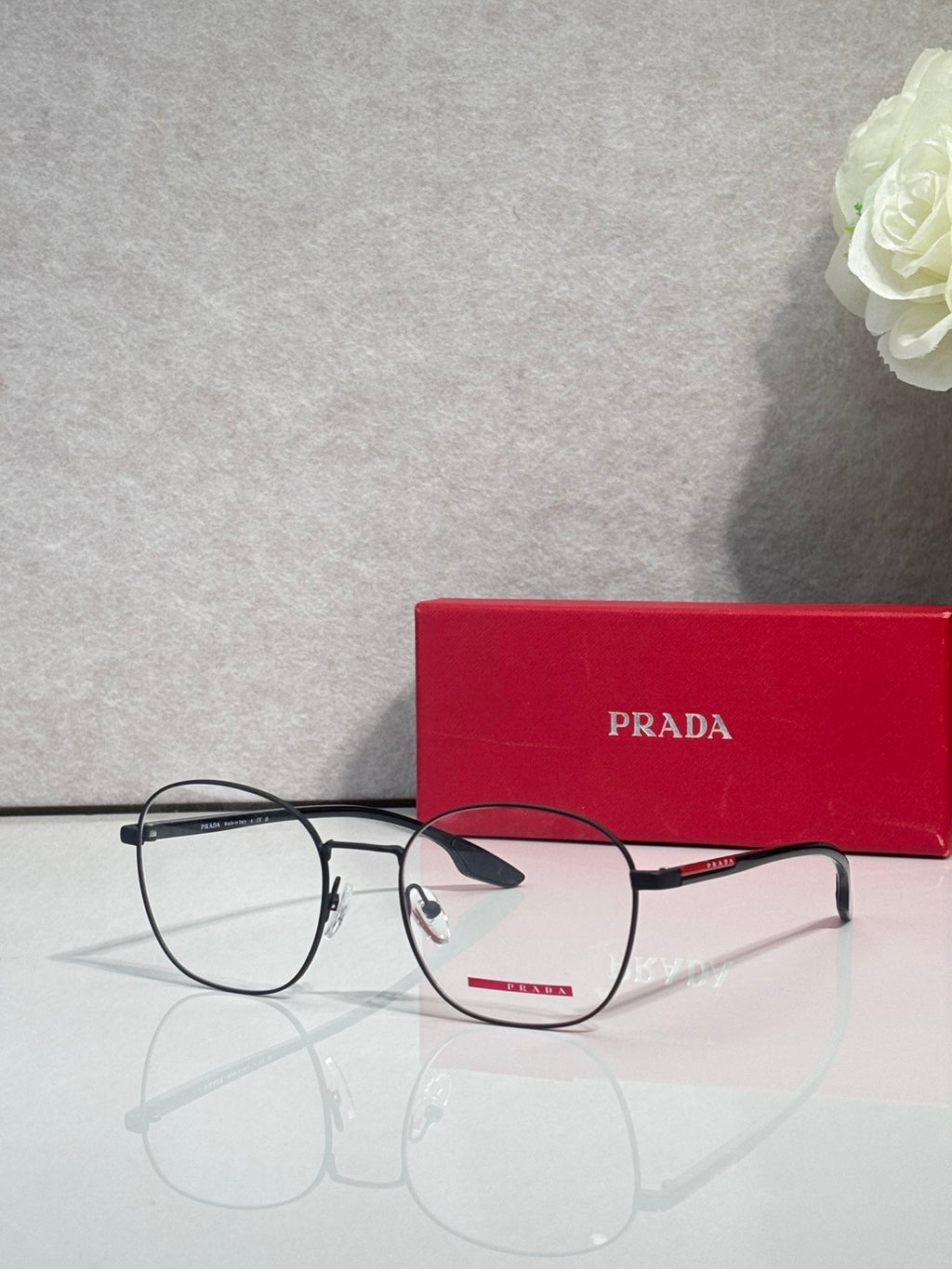 Prada eyeglasses, dark rectangular frames with clear lenses.
