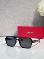 Prada black square sunglasses with dark gray lenses, red Prada case behind