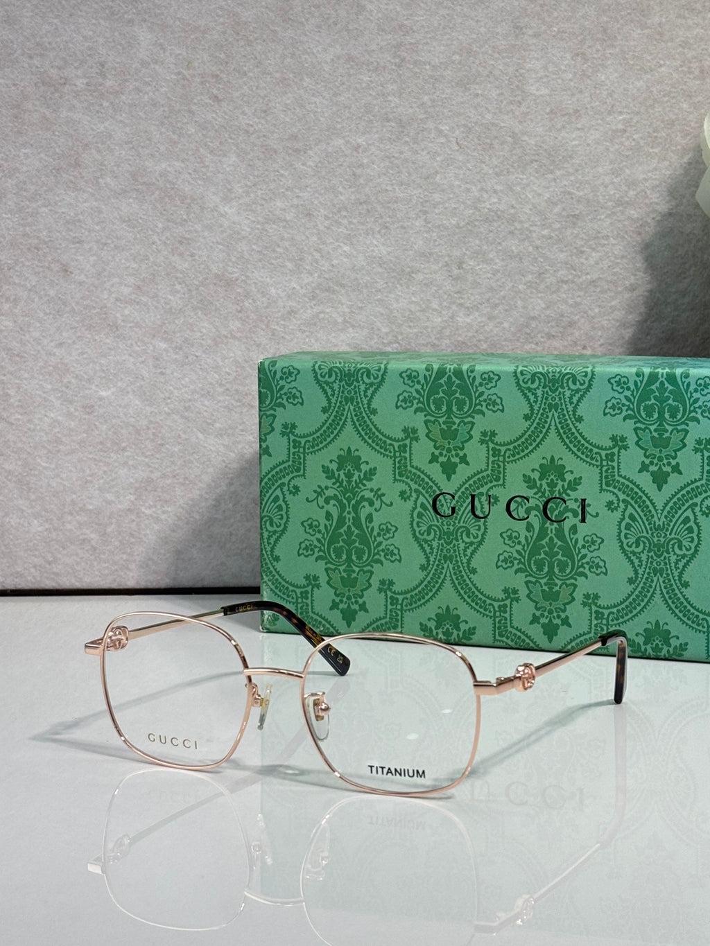 Gucci titanium eyeglasses with gold metal frame and clear lenses, logo at center front