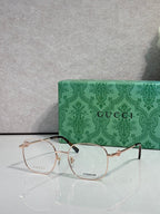 Gucci titanium eyeglasses with gold metal frame and clear lenses, logo at center front