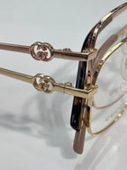 Gucci eyeglasses hinge detail with GG emblem, gold-tone metal and clear lenses