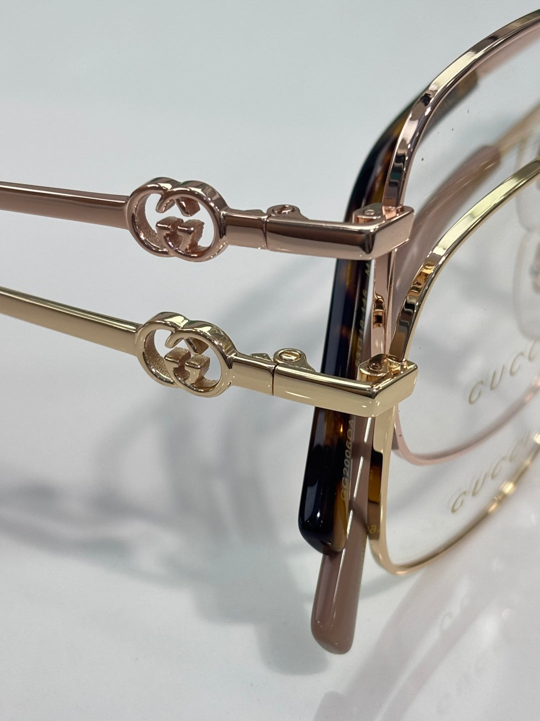 Gucci eyeglasses hinge detail with GG emblem, gold-tone metal and clear lenses