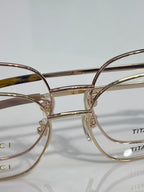 Gucci titanium eyeglasses frame close-up with gold-tone metal and engraved branding