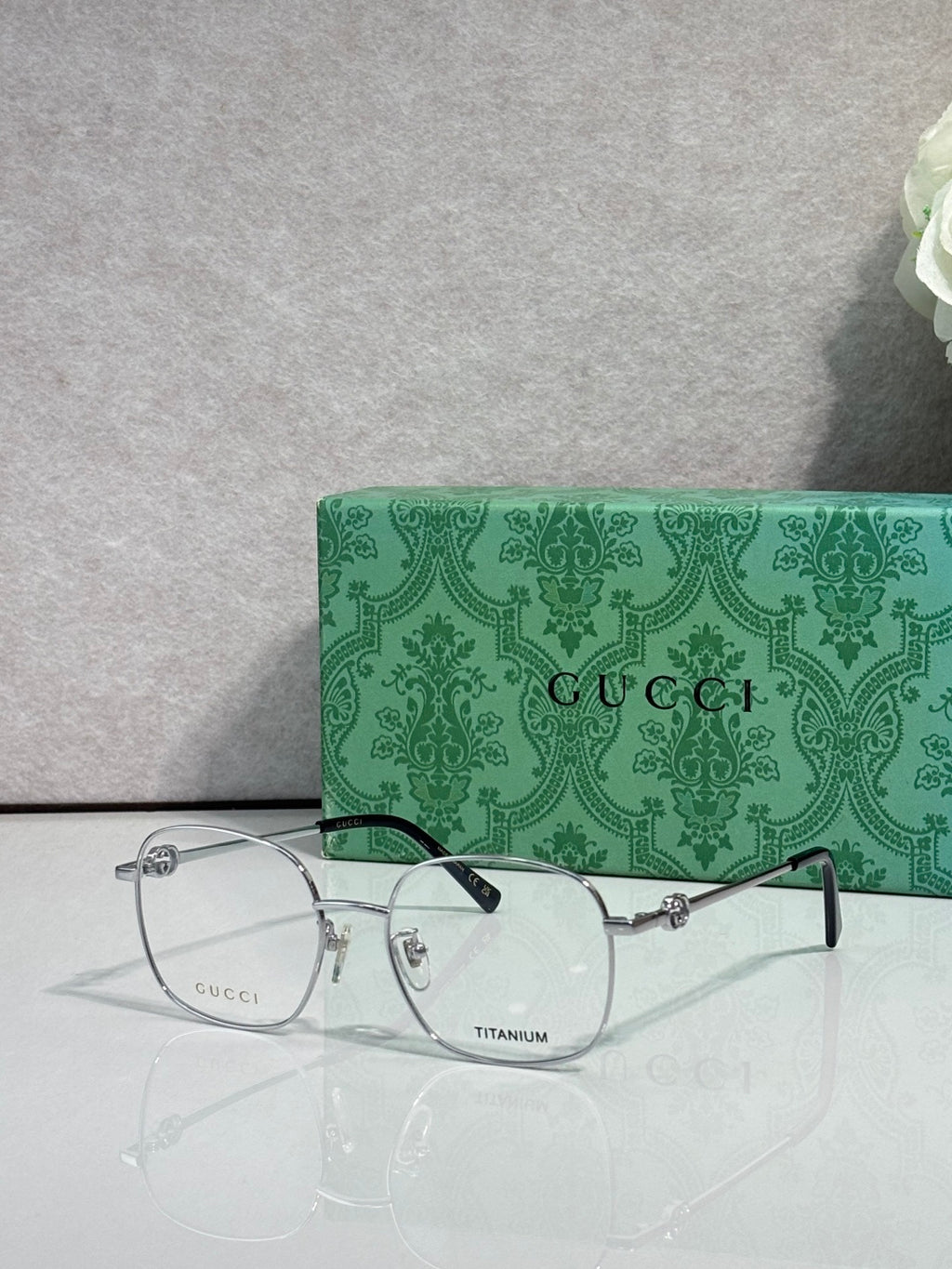 Gucci titanium eyeglasses with clear lenses and dark metal frame, branded temple accents