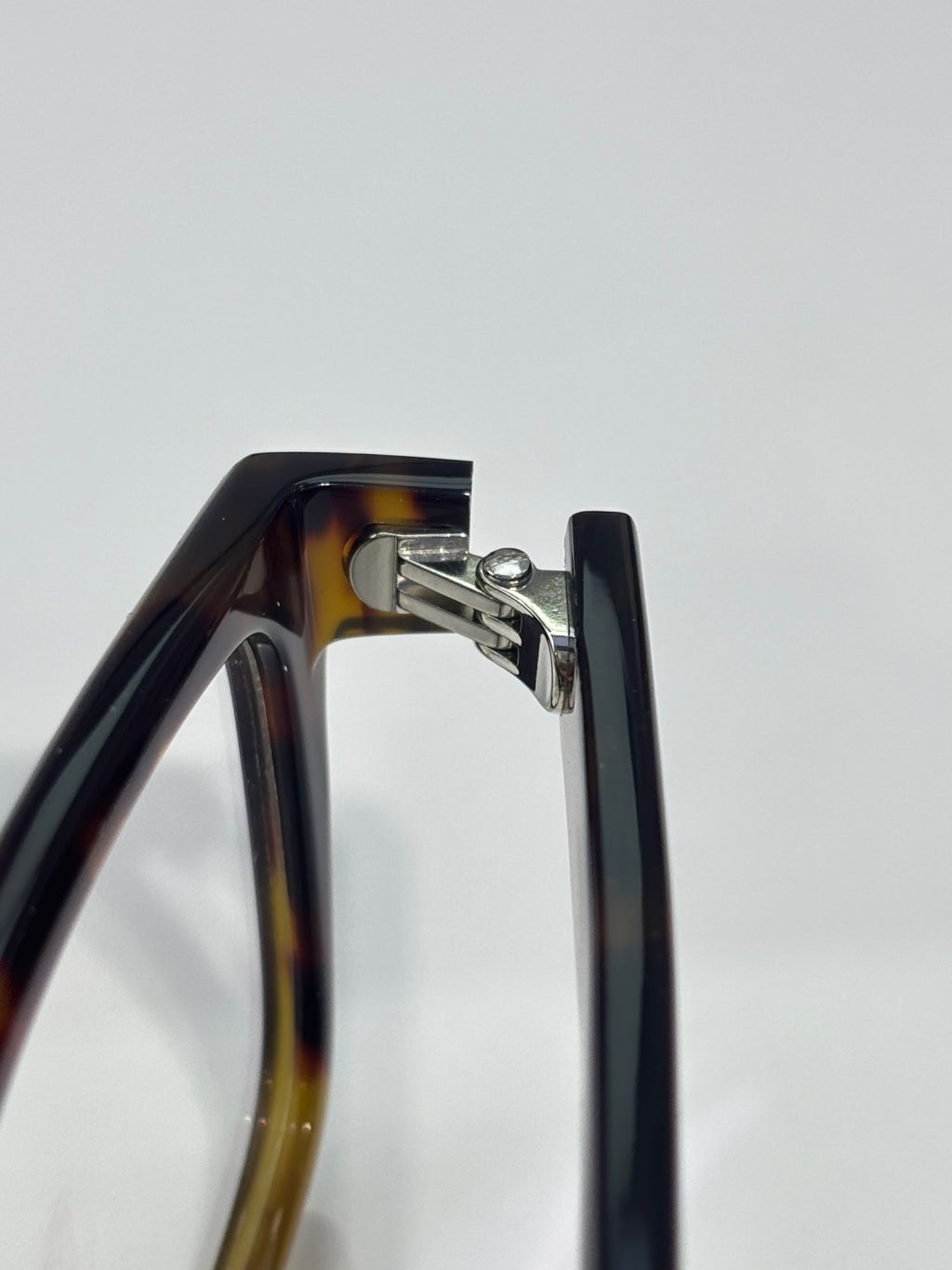 Prada dark eyeglasses hinge detail with metal bracket and acetate frame