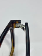 Prada dark eyeglasses hinge detail with metal bracket and acetate frame