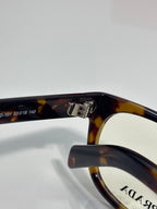 Prada glasses close-up of tortoise temple and bridge with PRADA logo.