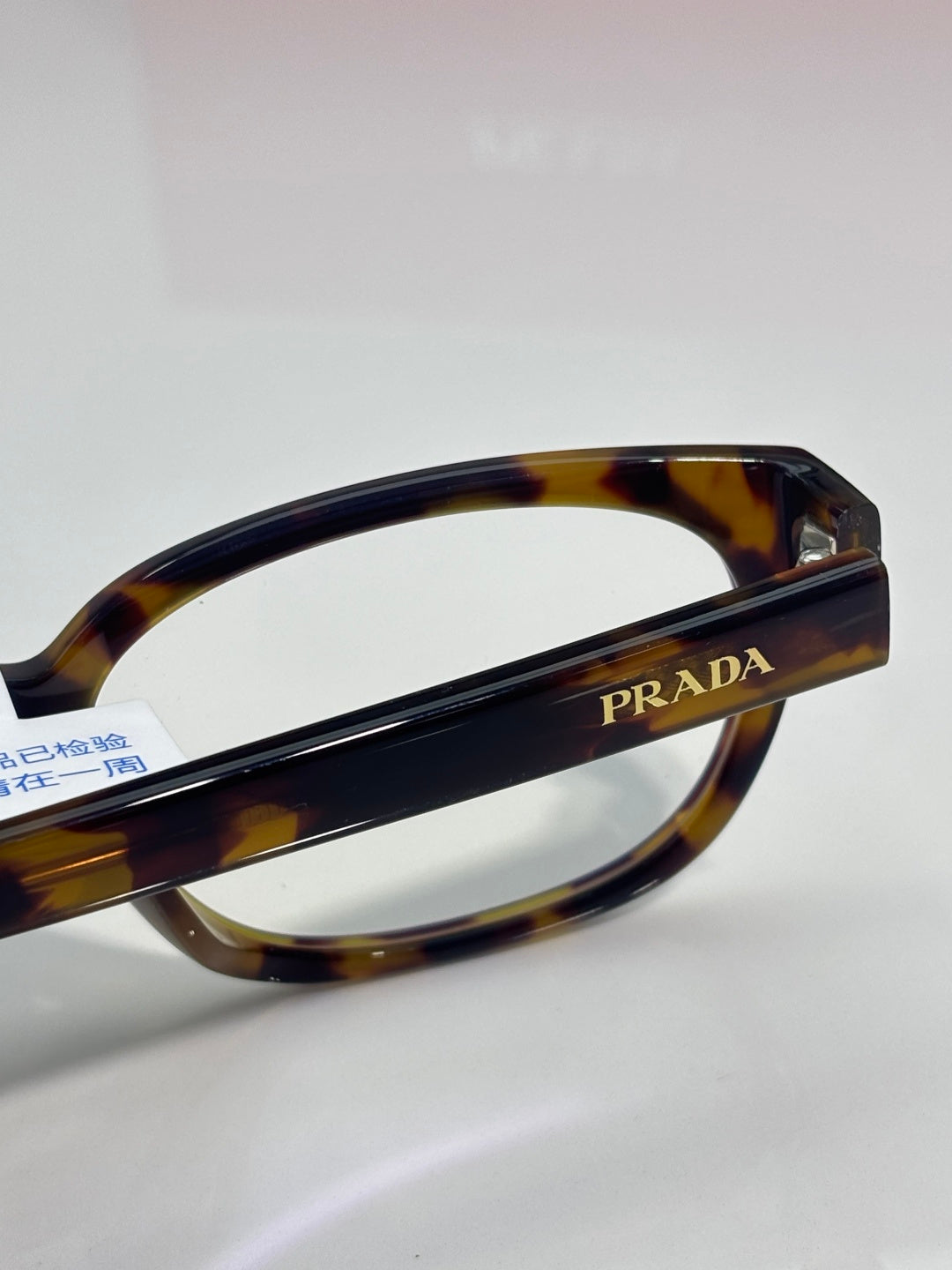 Prada glasses close-up of dark tortoise front rim with PRADA logo on arm.