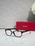 Prada glasses with dark tortoise frame, clear lenses, and PRADA logo on temple.