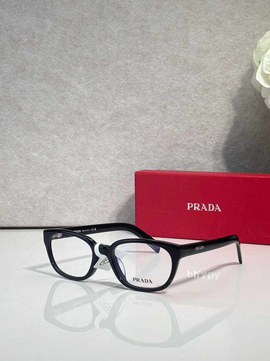 Prada glasses with black rectangular frame, clear lenses, and logo temples.