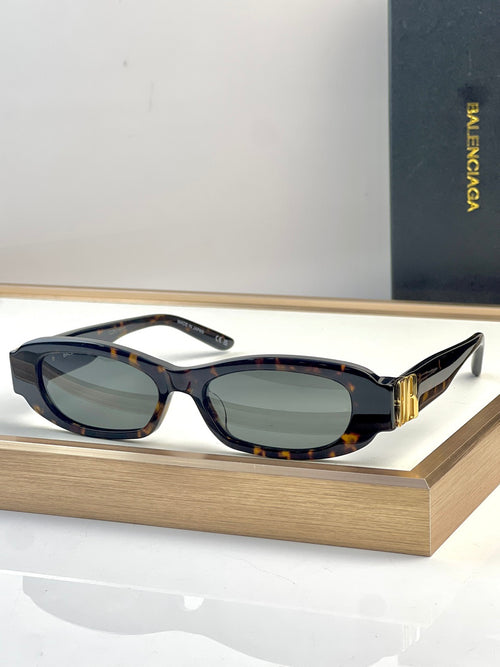 Balenciaga sunglasses with dark oval frames, multicolor speckled arms, green-tinted lenses.
