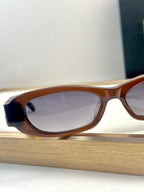 Balenciaga sunglasses close-up with brown oval frames and light-tinted lenses.