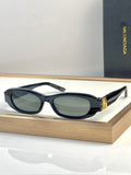 Balenciaga sunglasses with dark navy oval frames and green-tinted lenses, gold detail at temple.