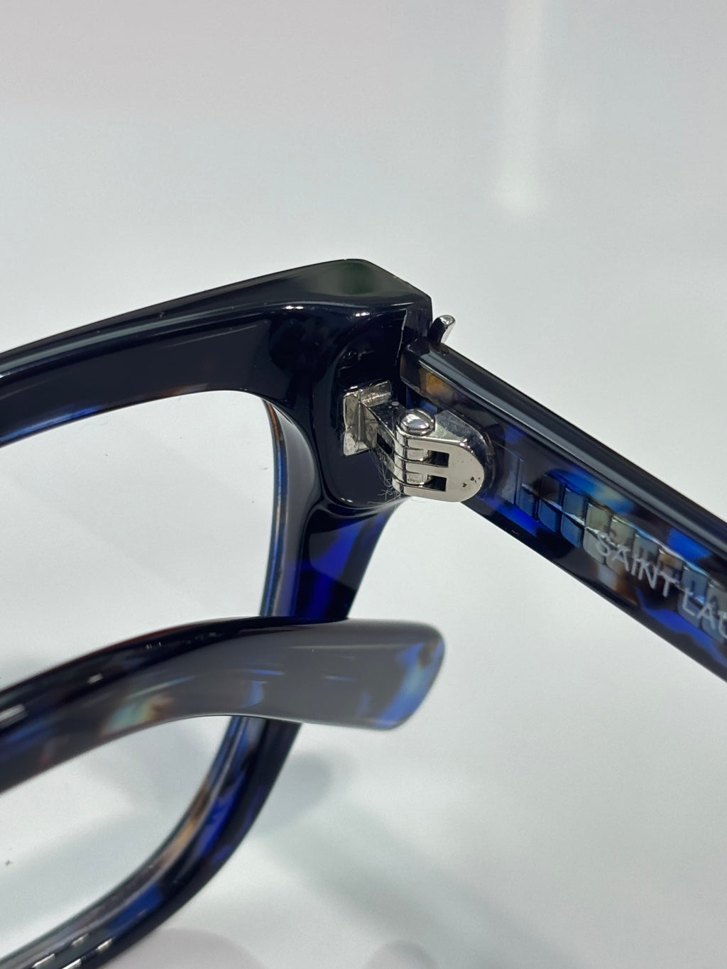 YSL blue-tinted eyeglasses arm and hinge close-up with logo on the bridge