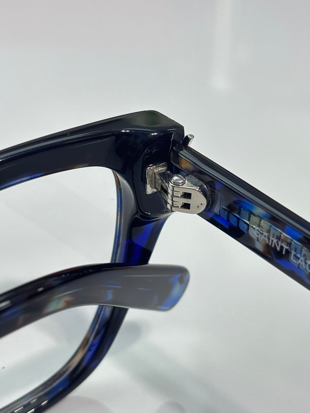 YSL blue-tinted eyeglasses arm and hinge close-up with logo on the bridge