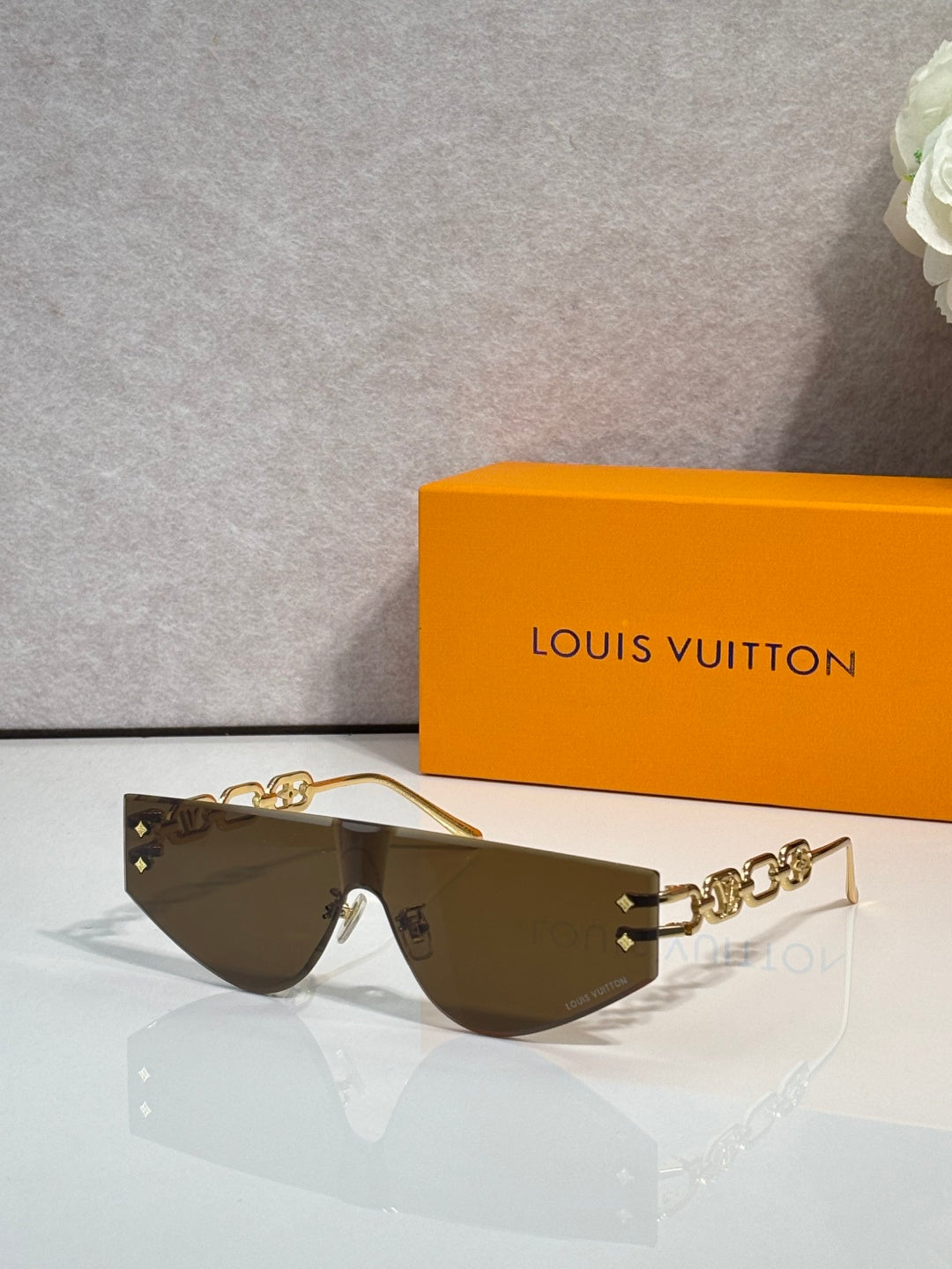 Louis Vuitton sunglasses with brown tinted lenses and gold-tone chain temple arms