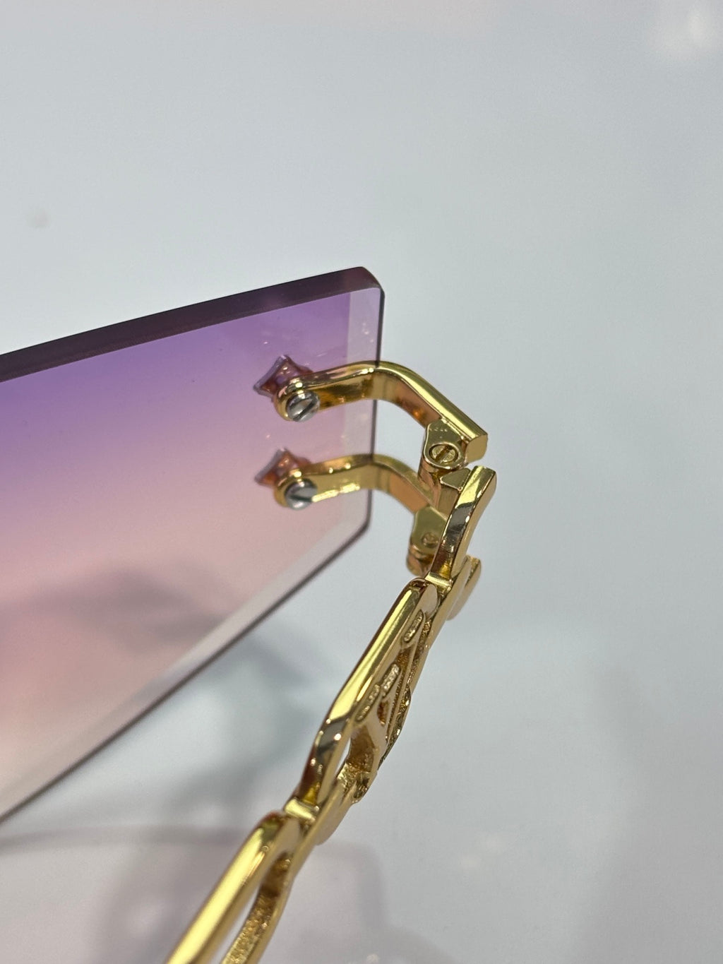 Louis Vuitton sunglasses close-up of gold-tone frame hinge and earhook with lens edge