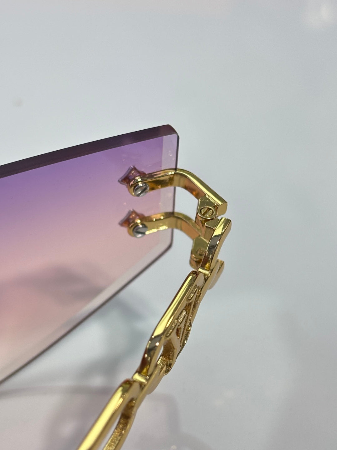 Louis Vuitton sunglasses close-up of gold-tone frame hinge and earhook with lens edge
