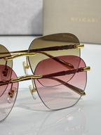 Gold metal round sunglasses with rose-tinted lenses and brown-tinted temple tips.