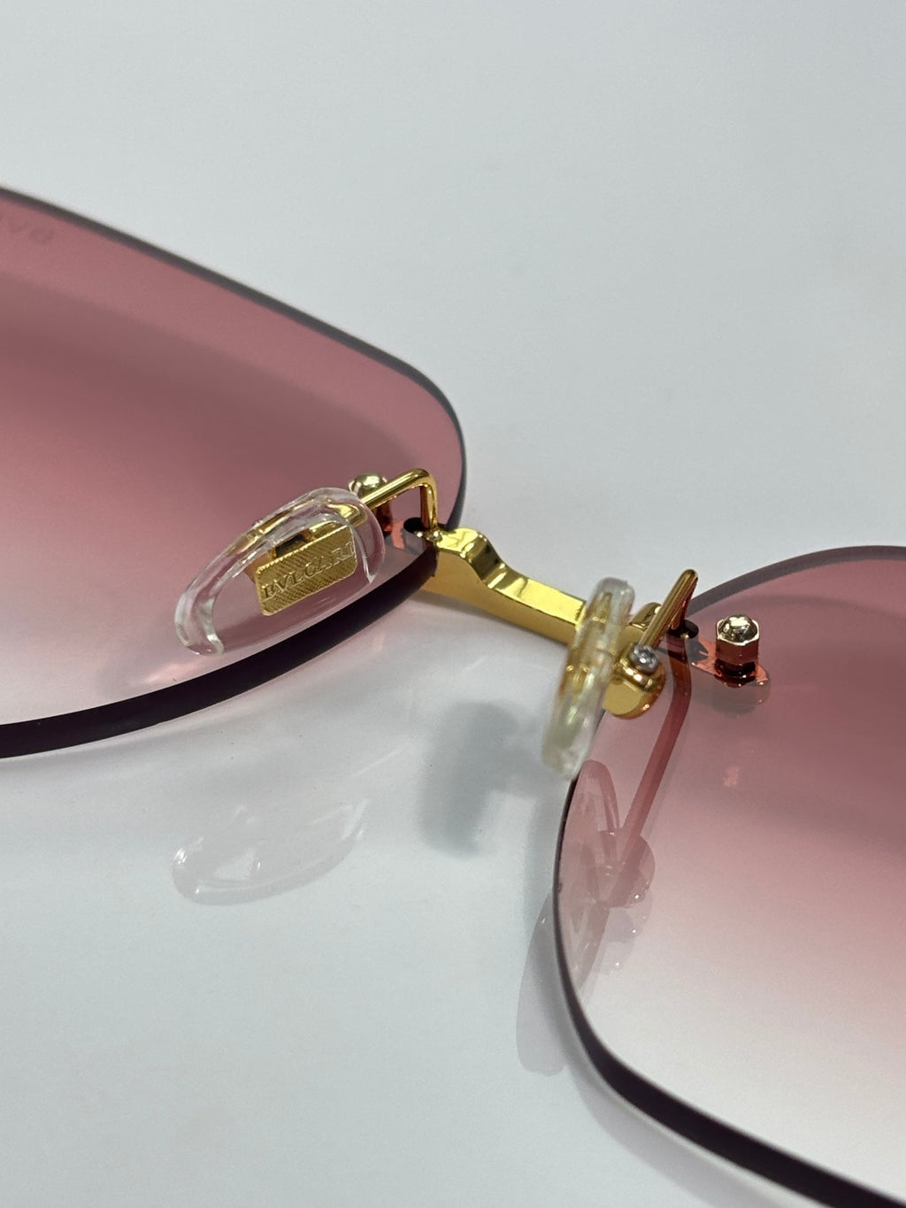 Rose-tinted round sunglasses with gold hinges and temple details; metal frame.