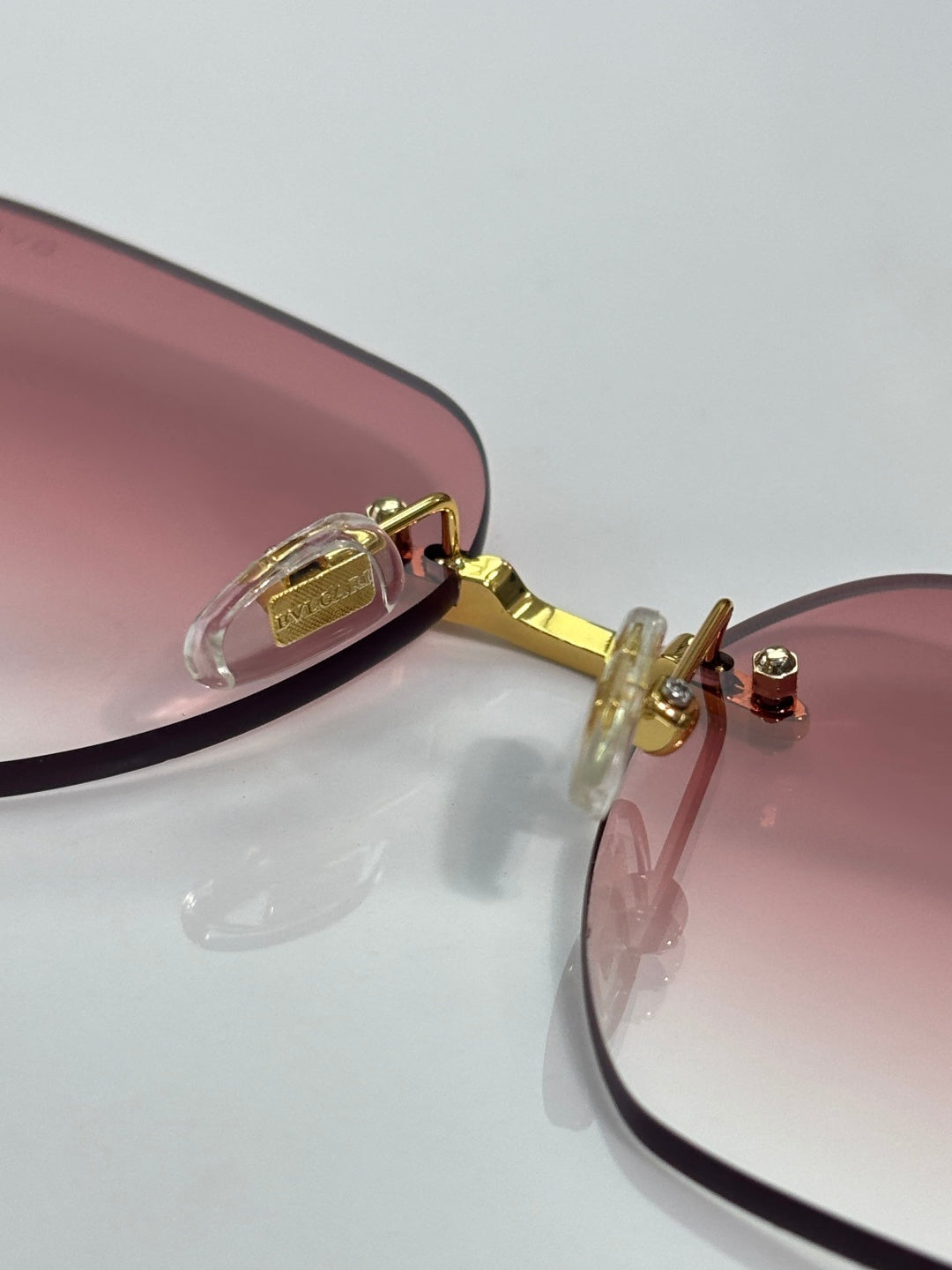 Rose-tinted round sunglasses with gold hinges and temple details; metal frame.