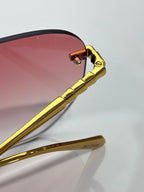Gold metal temple and hinge on rose-tinted round sunglasses; clear lens rim.