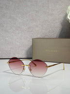 Round burgundy sunglasses with gold-tone frame and tinted pink-red lenses