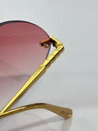 Gold-tone temple arm with engraved logo and burgundy-tinted lens edge