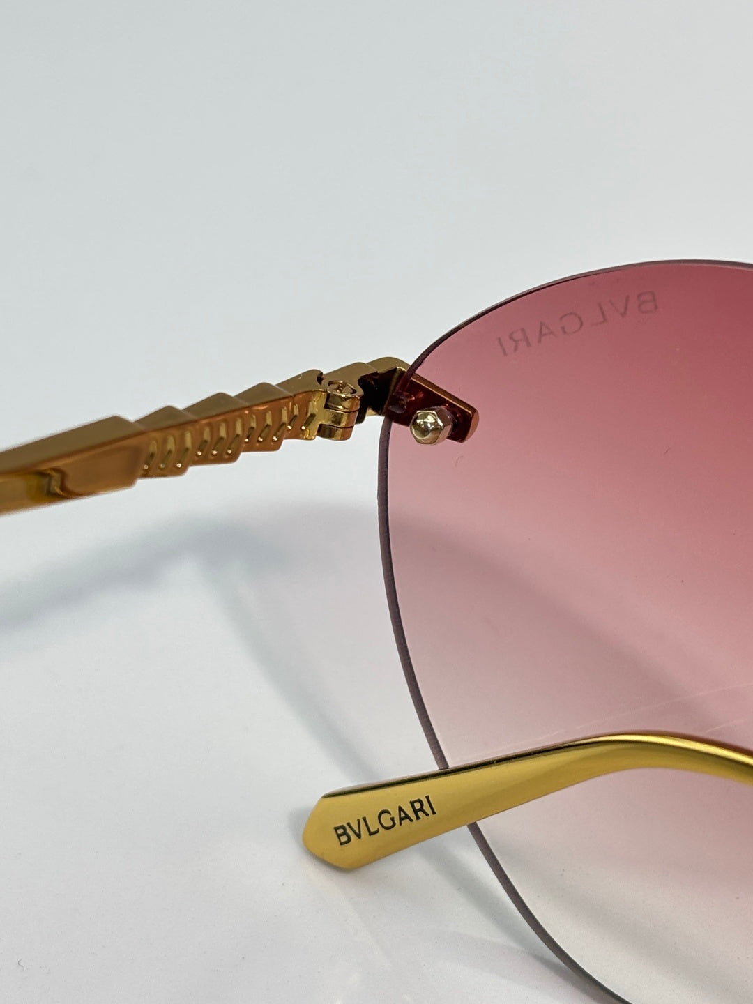 Close-up of burgundy lens and gold-tone hinge with engraved branding