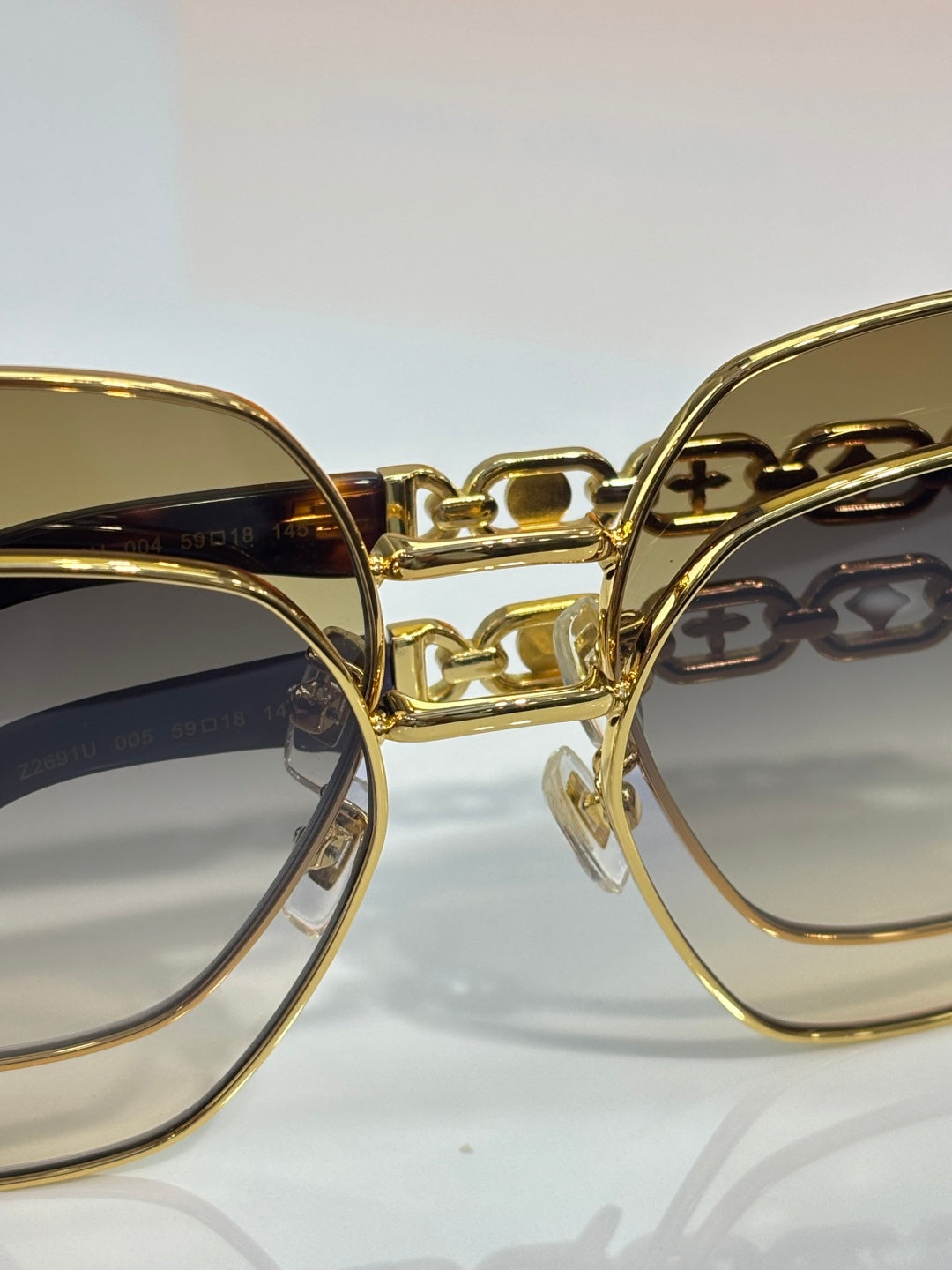 Louis Vuitton sunglasses close-up: gold-tone double bridge and dark lenses