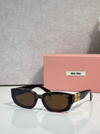 MiuMiu sunglasses with dark frames and brown-tinted cat-eye lenses