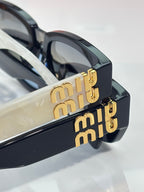 MiuMiu sunglasses close-up with gold-tone logo on the temple