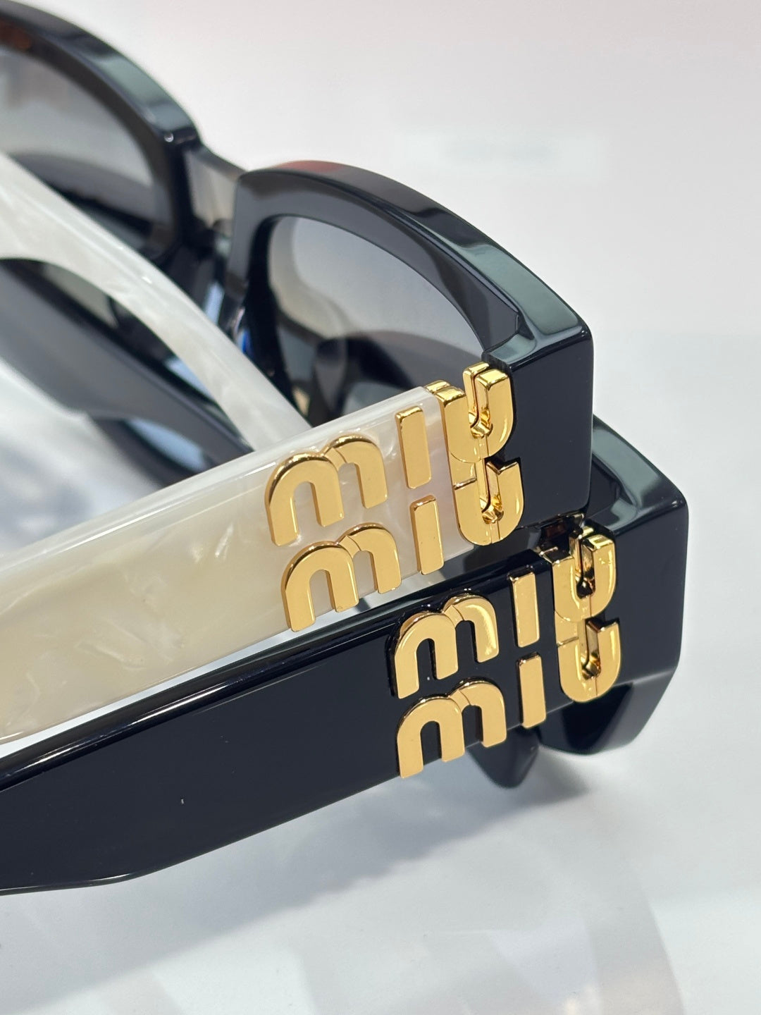 MiuMiu sunglasses close-up with gold-tone logo on the temple